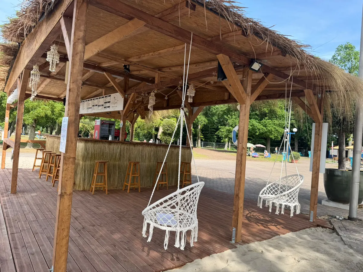 Strandbar mit Strohdach und Hängesesseln im Beach Club