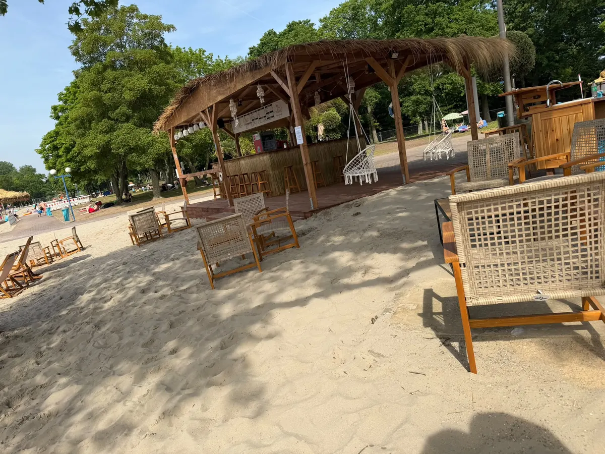 Strandbar mit Strohdach und Hängesesseln vom Sandstrand aus