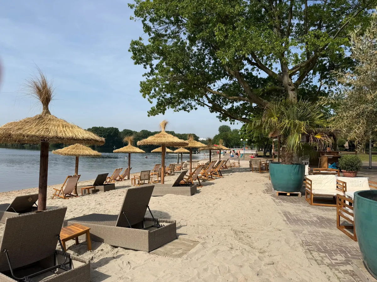 Sonnenliegen und Strohschirme am Ufer des Wolfssees