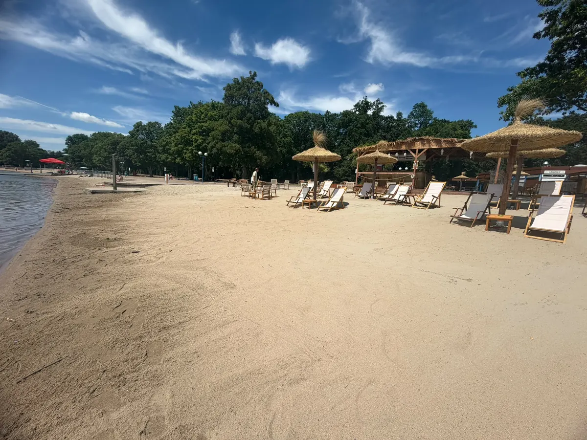 Weiter Sandstrand mit Strohschirmen im Beach Club