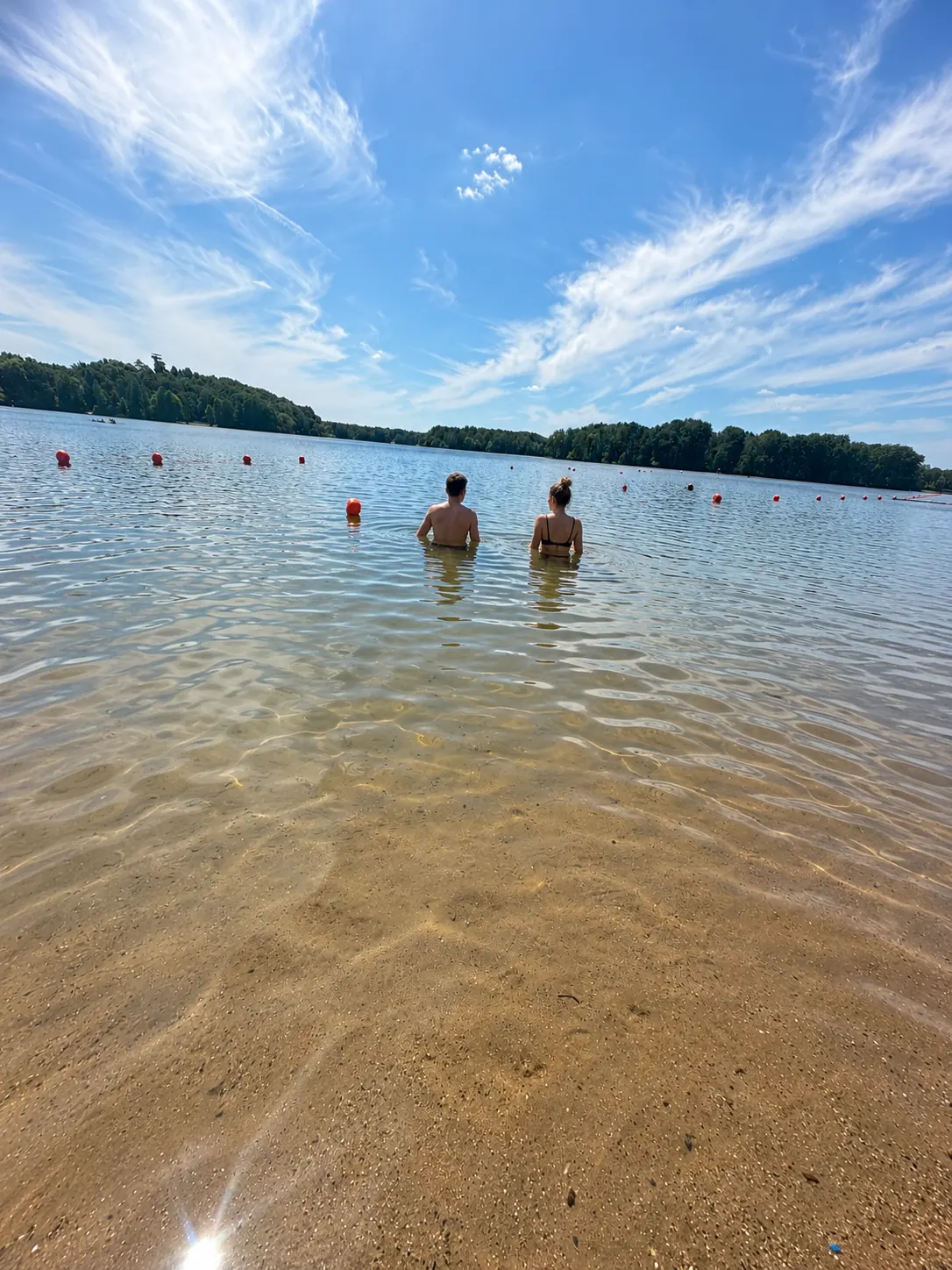 Badegäste im klaren, flachen Wasser des Wolfssees