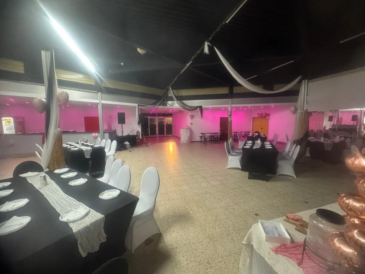 Indoorraum mit pinker Beleuchtung und eingedeckten Tischen