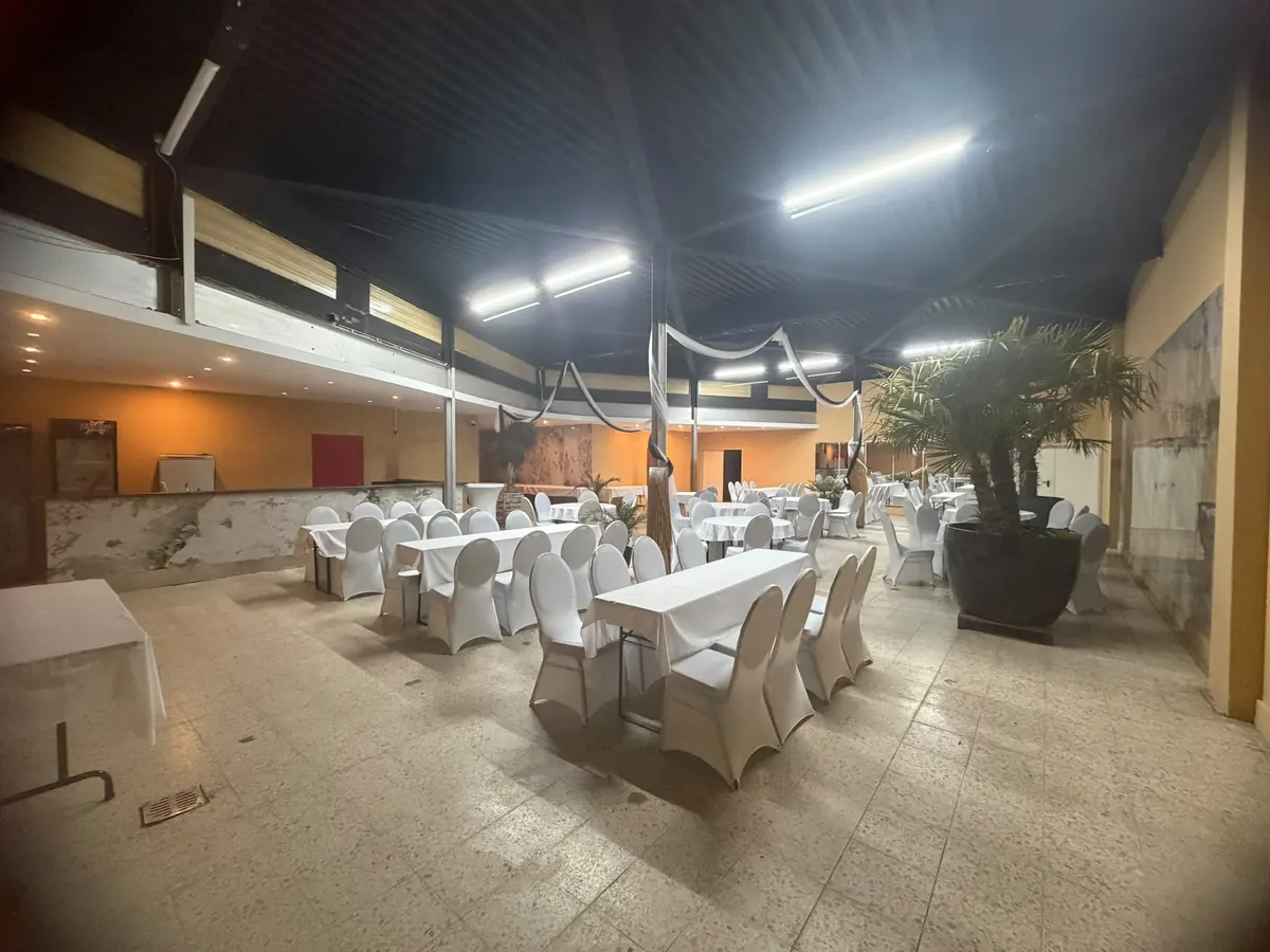 Lange Festtafeln mit weißen Stuhlhussen im Indoorraum