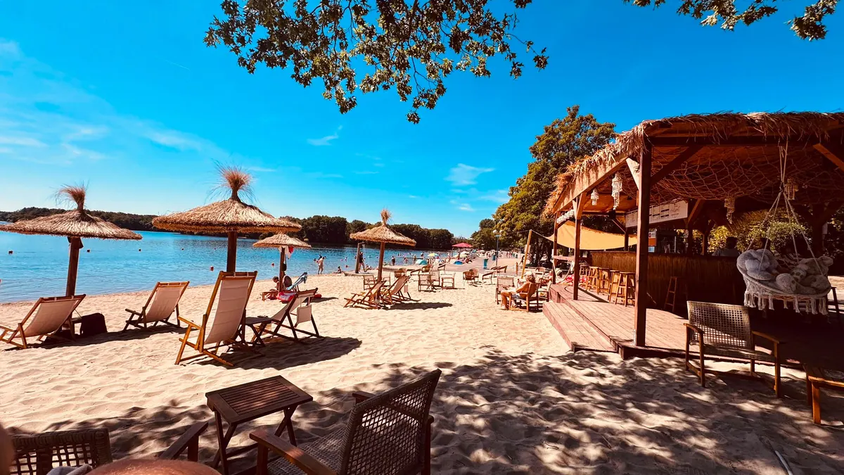 Sandstrand mit Strohschirmen und Strandbar am Wolfssee in Duisburg